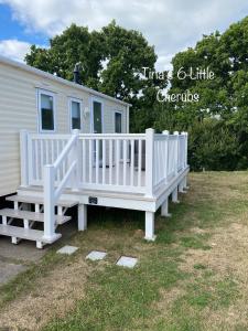 a white house with a porch and a white fence at 3 bedroom holiday home in Thorness bay in Cowes