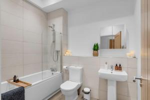 a white bathroom with a tub and a toilet and a sink at Norwich Castle View Apt - Modern 2 Br in Norwich