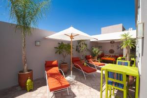 un patio con sillas naranjas y una sombrilla en Riad Mylaya, en Marrakech