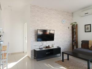 a living room with a flat screen tv on a brick wall at נוגה בגולן in Qasrîne