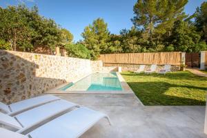 a backyard with a swimming pool and lounge chairs at Villa with pool near the beach in Cala San Vicente by Renthousing in Cala de Sant Vicent