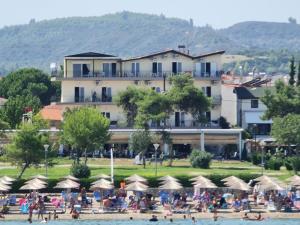 un gruppo di persone sulla spiaggia di fronte a un hotel di Plaza Hotel a Hanioti
