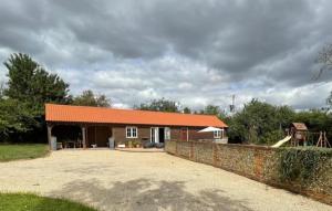 Toppesfield的住宿－Walnut Tree Cottage Barn，一座带橙色屋顶和石墙的房子