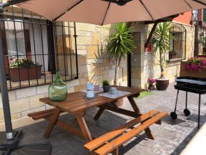 een houten tafel en bank onder een paraplu bij El valle de Lis in Praves
