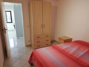 1 dormitorio con armario de madera y cama roja en CASA VACANZA DA ZIO NINO en Capo Vaticano