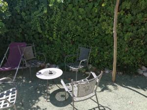 three chairs and a table in front of a hedge at Petite maison et son jardinet en Village. in Puisserguier