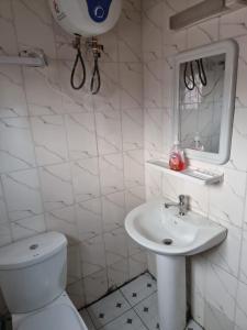a white bathroom with a toilet and a sink at Baobab Lodge Douala (Bonamoussadi) in Douala
