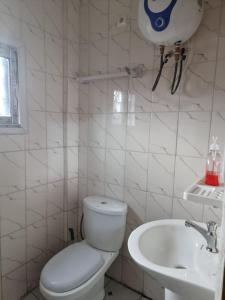 a white bathroom with a toilet and a sink at Baobab Lodge Douala (Bonamoussadi) in Douala