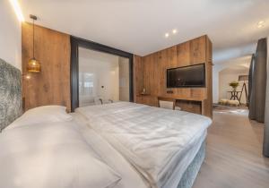 a bedroom with a large white bed and a flat screen tv at Hotel Hell in Ortisei