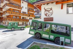 zwei grüne Fahrzeuge, die vor einem Gebäude geparkt sind in der Unterkunft Hotel Jägerhof in Zermatt