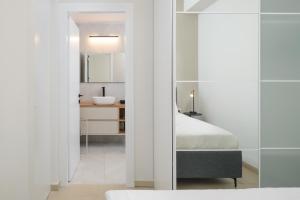 ein Schlafzimmer mit einem Bett und ein Badezimmer mit einem Spiegel in der Unterkunft Elegant Duplex with XL Patio by FeelHome in Tel Aviv