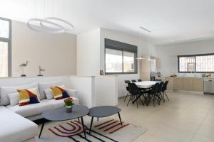 Biały salon z białą kanapą i stołem w obiekcie Elegant Duplex with XL Patio by FeelHome w Tel Awiwie