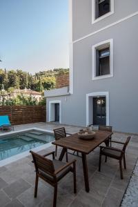 萨摩斯Villa Samos - Renovated stone villa with private pool- 2 min from the sea!的游泳池旁边有一张桌子和椅子的露台