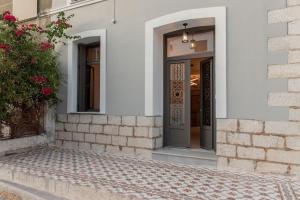 une porte d'entrée d'un bâtiment blanc avec une usine dans l'établissement Villa Samos - Renovated stone villa with private pool- 2 min from the sea!, à Samos