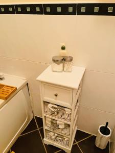 un comodino bianco con una bottiglia in bagno di A Room in Central Park Apts a Carrick on Shannon