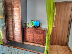 een kamer met een televisie en een dressoir met groene gordijnen bij ORIENTE BedRoom&Sea, a 5 minuti dal mare con clima,TV, zanzariere, doccia esterna , parcheggio e veranda in Castiadas