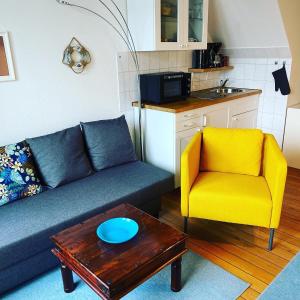 a living room with a blue couch and a yellow chair at Kajüthus Apartment 2 in Fehmarn