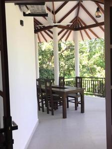 eine Veranda mit einem Tisch, Stühlen und einem Sonnenschirm in der Unterkunft Lush Green Villa in Talpe