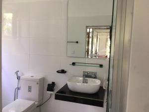 a white bathroom with a sink and a toilet at Lush Green Villa in Talpe