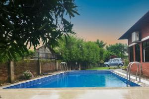 a swimming pool in a yard with a car in the background at Vision Safari Pvt Ltd in Sauraha