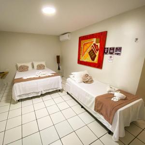 Cette chambre comprend deux lits et un tableau mural. dans l'établissement Mon Chéri - Pousada Exclusive, à Japaratinga