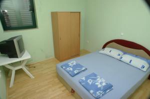 um pequeno quarto com uma cama e uma televisão em Apartments by the sea Marusici, Omis - 2741 em Mimice