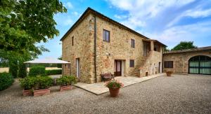 a large stone building with a table and a umbrella at Agriturismo il Canneto in Casole dʼElsa