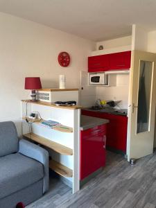 a small kitchen with red cabinets and a blue couch at Fréjus, Studio dans résidence avec Piscine in Fréjus