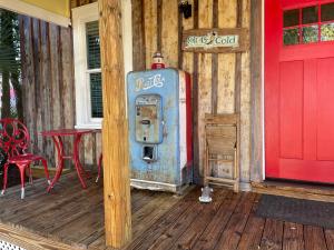 uma bomba de gasolina velha num alpendre com uma porta vermelha em 150 year old Restored Lincolnville cottage em St. Augustine