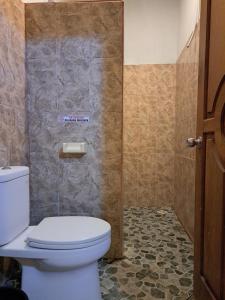 a bathroom with a toilet and a tiled wall at Cozy Alfia Inn in Gili Trawangan