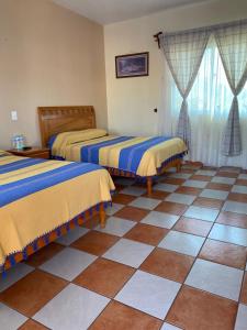 een kamer met 2 bedden en een tegelvloer bij Hotel El Mirador in Tequisquiapan