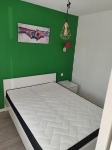 克松吕-隆日梅le Cozy du Poli的卧室配有绿色墙壁上的白色床垫