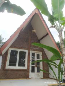 a house with a window and a tree at Green Haven Homestay in Tetebatu
