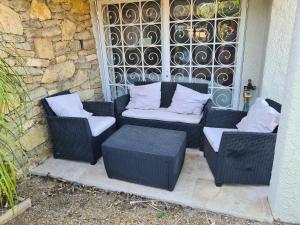 2 Korbstühle und ein Tisch auf einer Terrasse in der Unterkunft Bas de villa T3 Ollioules avec Piscine Vue mer in Ollioules