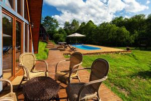 een terras met stoelen, een parasol en een zwembad bij Dosbajka in Małastów