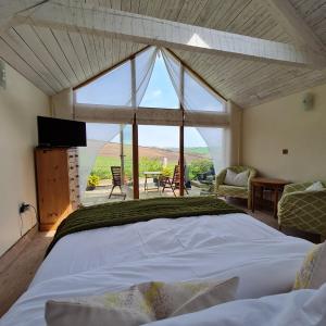a bedroom with a large bed and a large window at The Old Pottery, Unique Views & Spa-like Bathroom in Ashburton
