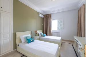 1 dormitorio con 2 camas y ventana en villa Pergola en Hammamet