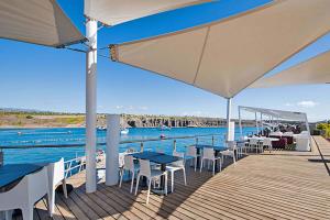 una terrazza con tavoli, sedie e acqua di Villa Blue Marlin 8 a Pasito Blanco