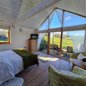a bedroom with a bed and a large glass window at The Old Pottery, Unique Views & Spa-like Bathroom in Ashburton