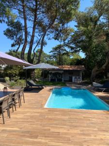 a swimming pool with chairs and umbrellas and a house at Villa de charme avec piscine à 500m des plages in Soorts-Hossegor