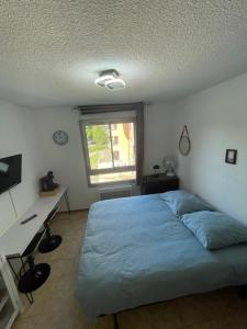 een slaapkamer met een bed, een bureau en een raam bij Les Logis de Paray Appartement 201 in Paray-le-Monial