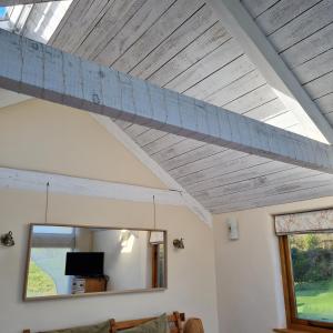 a living room with a wooden ceiling and a mirror at The Old Pottery, Unique Views & Spa-like Bathroom in Ashburton