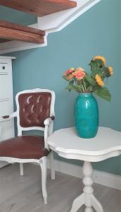 a vase of flowers sitting next to a white chair at Kajüthus Apartment 2 in Fehmarn