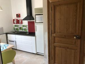 a kitchen with a wooden door and a white refrigerator at Maison au calme au coeur de village in Saint-Georges-dʼOrques