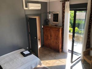 a bedroom with a bed and a door leading to a porch at Maison au calme au coeur de village in Saint-Georges-dʼOrques