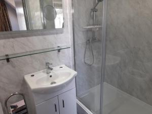 een badkamer met een witte wastafel en een douche bij Comfort House in Havant