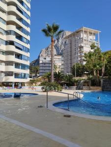 una piscina con palmeras y edificios en Appartement équipé CALPE Espagne, 4 couchages, terrasse, piscines, climatisation, garage et WIFI gratuits, en Calpe