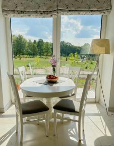 una mesa y sillas blancas en una habitación con ventana en Komfortowy domek z kominkiem en Barwice