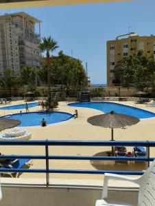 Blick auf einen Pool mit Menschen und Sonnenschirmen in der Unterkunft Appartement équipé CALPE Espagne, 4 couchages, terrasse, piscines, climatisation, garage et WIFI gratuits in Calpe