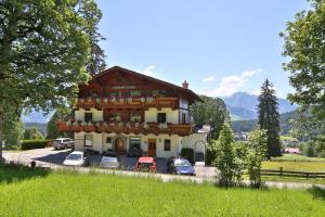 a large house with cars parked in front of it at Pension Sonnwendhof in Ramsau am Dachstein